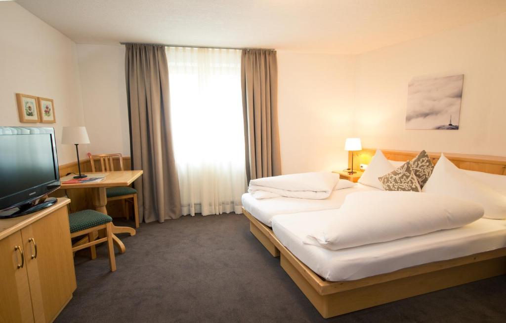 a hotel room with two beds and a television at Hotel Montfort in Sankt Anton am Arlberg