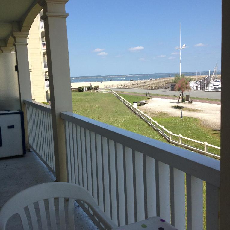 d'un balcon avec une chaise et une vue sur la plage. dans l'établissement T3 NEUF VUE PANORAMIQUE sur Mer PREMIERE LIGNE, à Arcachon