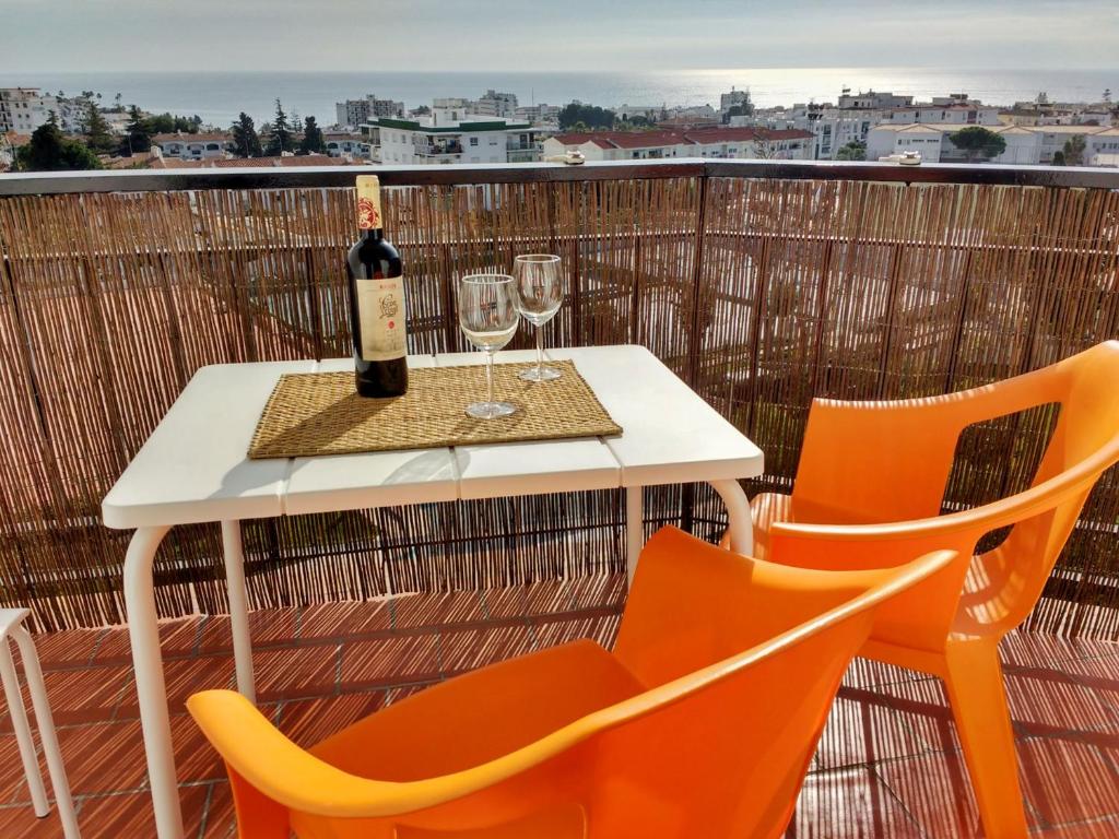 una mesa blanca con 2 sillas y una botella de vino en Apartamento Picasso, en Nerja