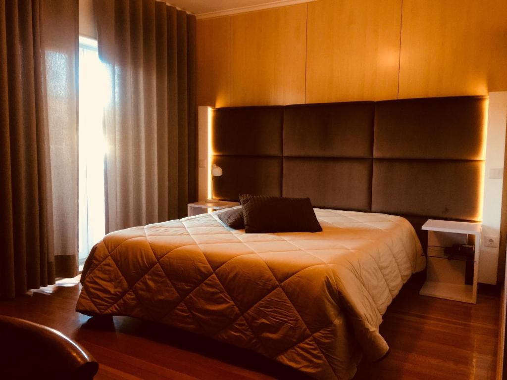 1 dormitorio con 1 cama con cabecero grande y ventana en Hotel Europa en Vila Pouca de Aguiar