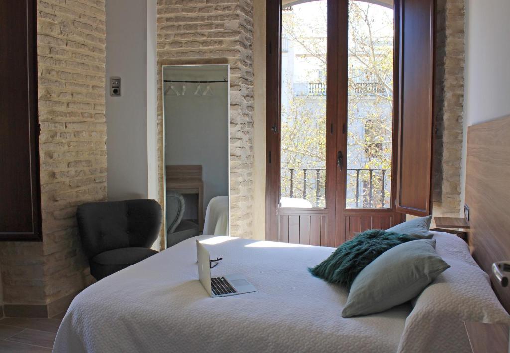 1 dormitorio con 1 cama con ordenador portátil en Apartamentos Reyes Catolicos 14, en Sevilla
