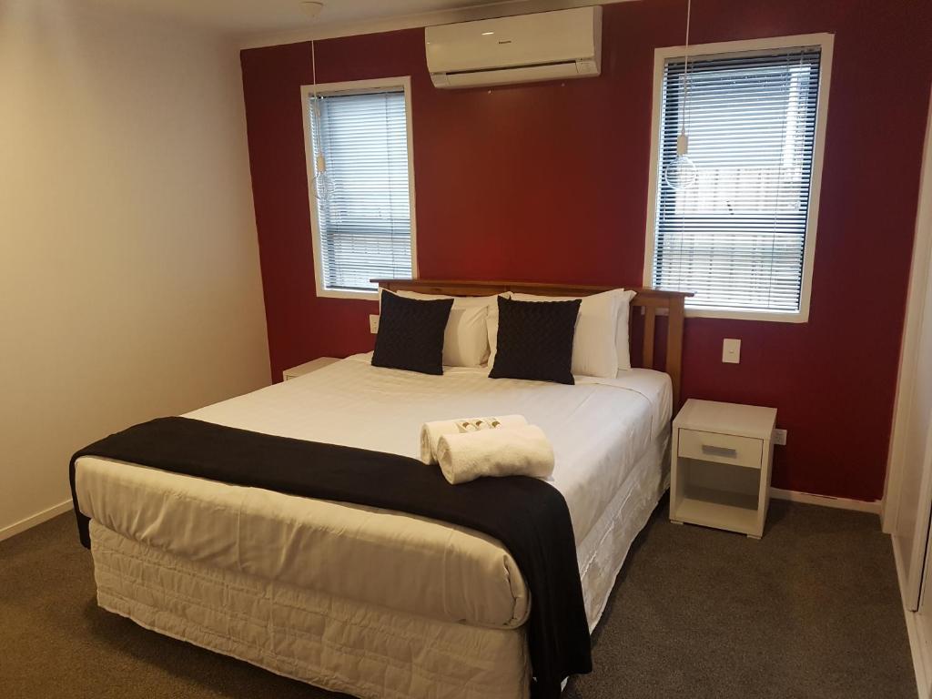 羅托魯阿的住宿－Trendy Bungalow in the Heart of Rotorua，一间卧室设有一张大床,拥有红色的墙壁和窗户。