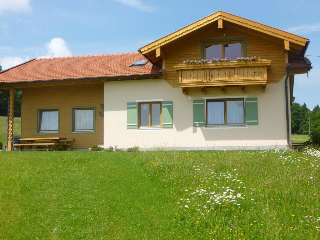 ein Haus mit einem Balkon auf einem grünen Feld in der Unterkunft Gästehaus Annemarie in Rimsting