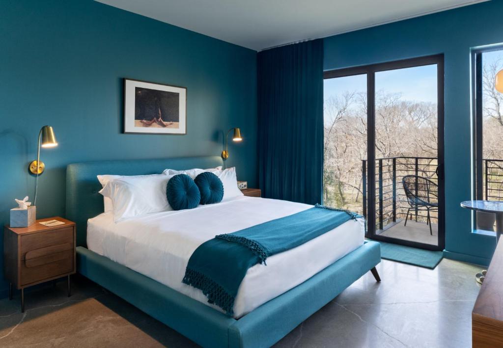 a blue bedroom with a bed and a balcony at The Ruby Hotel in Round Rock