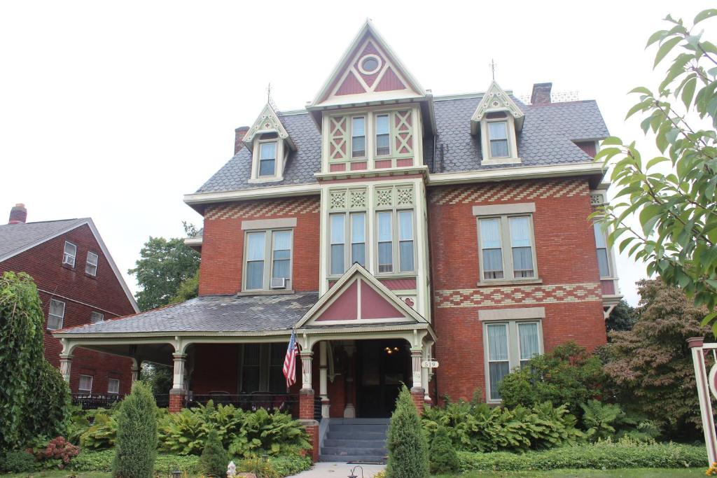 ein großes rotes Backsteinhaus mit einer Flagge davor in der Unterkunft Spencer House Bed & Breakfast in Erie