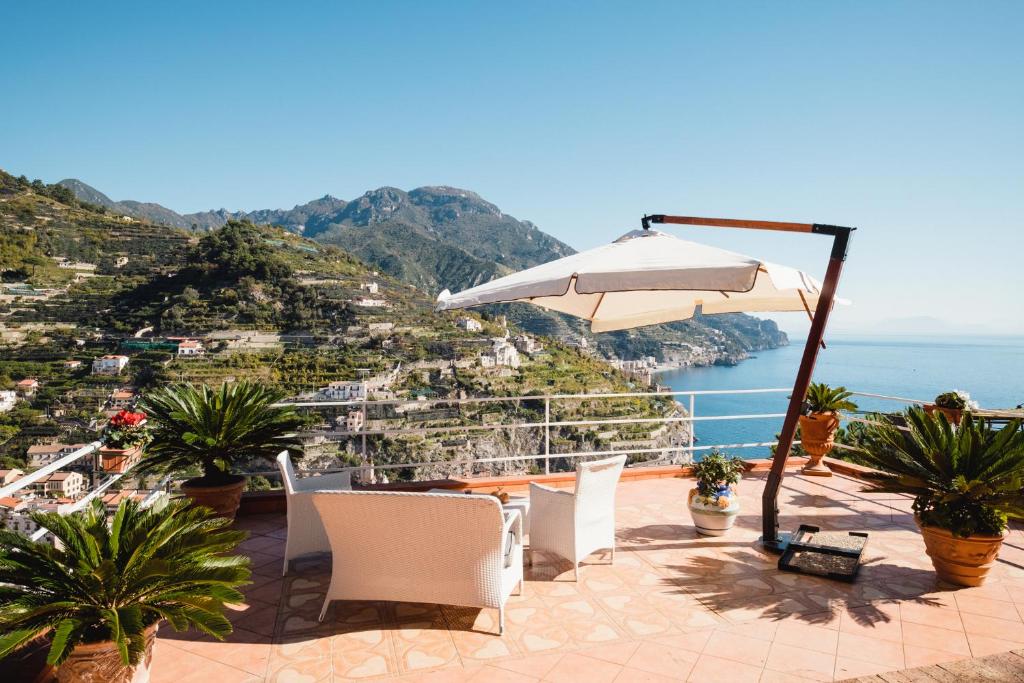 a patio with an umbrella and chairs and the ocean at B&B Orto Paradiso in Minori