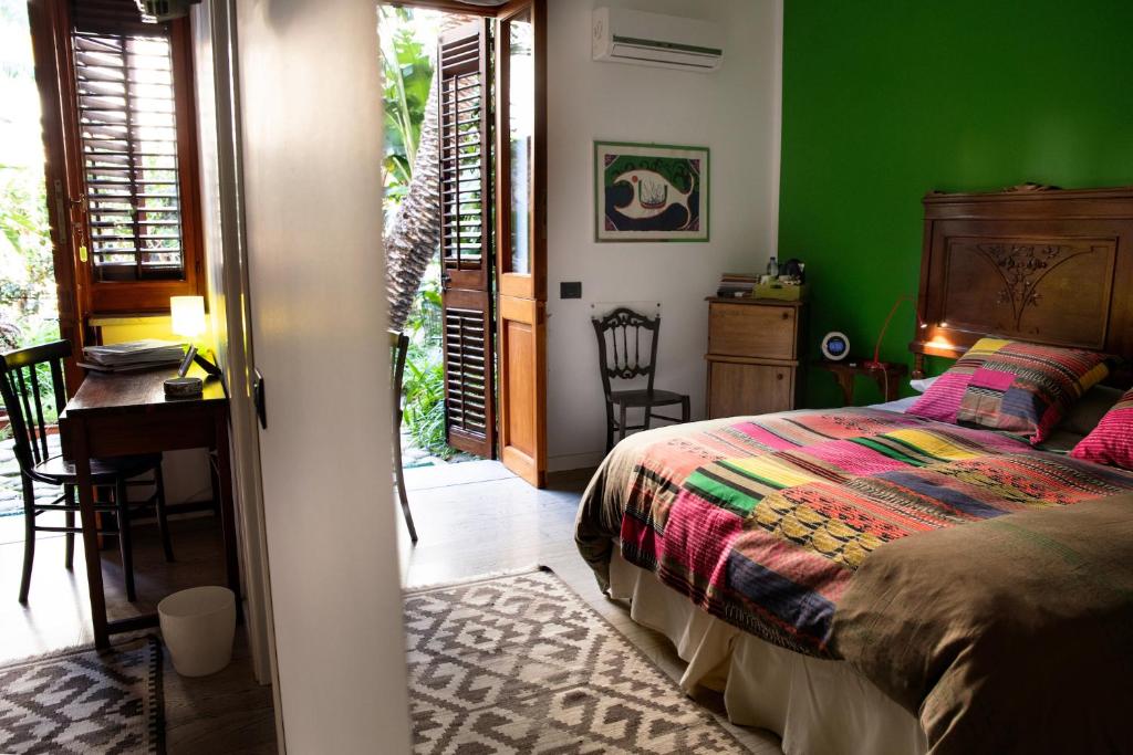 1 dormitorio con cama, escritorio y paredes verdes en Lirma B&B, en Cefalú