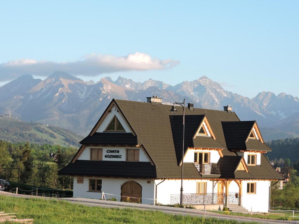ein Haus mit einem Dach mit Bergen im Hintergrund in der Unterkunft Chata Koziniec przy wyciągu in Czarna Góra