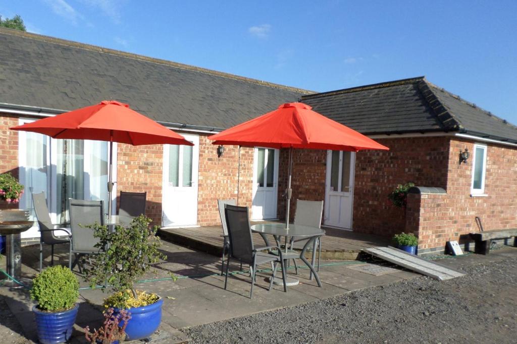 a patio with tables and chairs and red umbrellas at Ramsley Fields Apartments in Melbourne