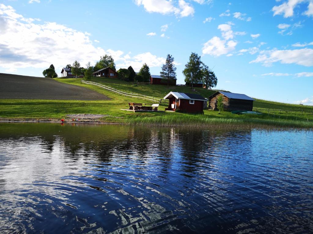 une maison sur une colline à côté d'une masse d'eau dans l'établissement Skatauddens Lantgård, à Älvsbyn