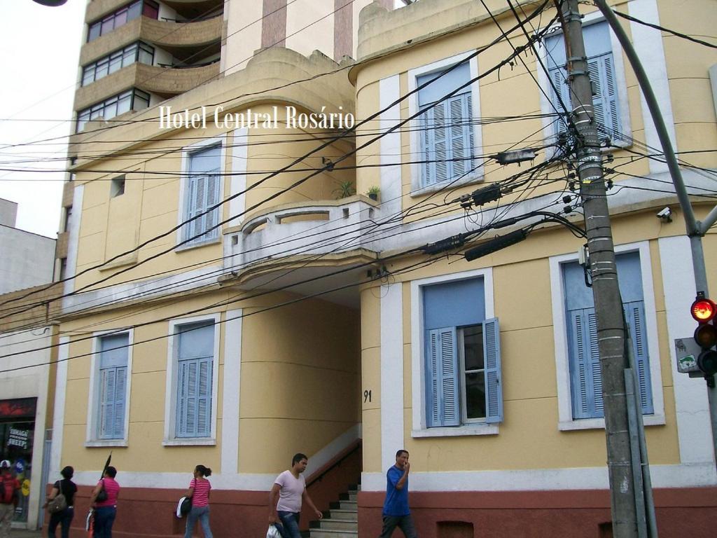 a building with people walking in front of it at Hotel Central Rosário in Jundiaí