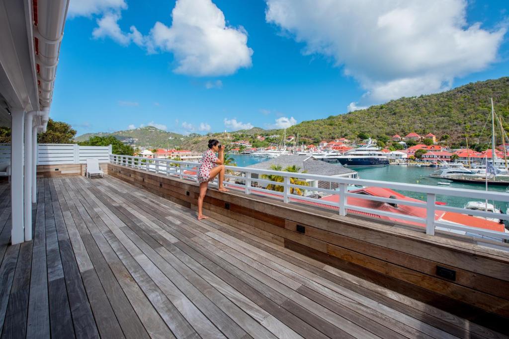 Eine Frau steht auf einem Balkon mit Blick auf den Jachthafen. in der Unterkunft Penthouse de Luxe Gustavia in Gustavia