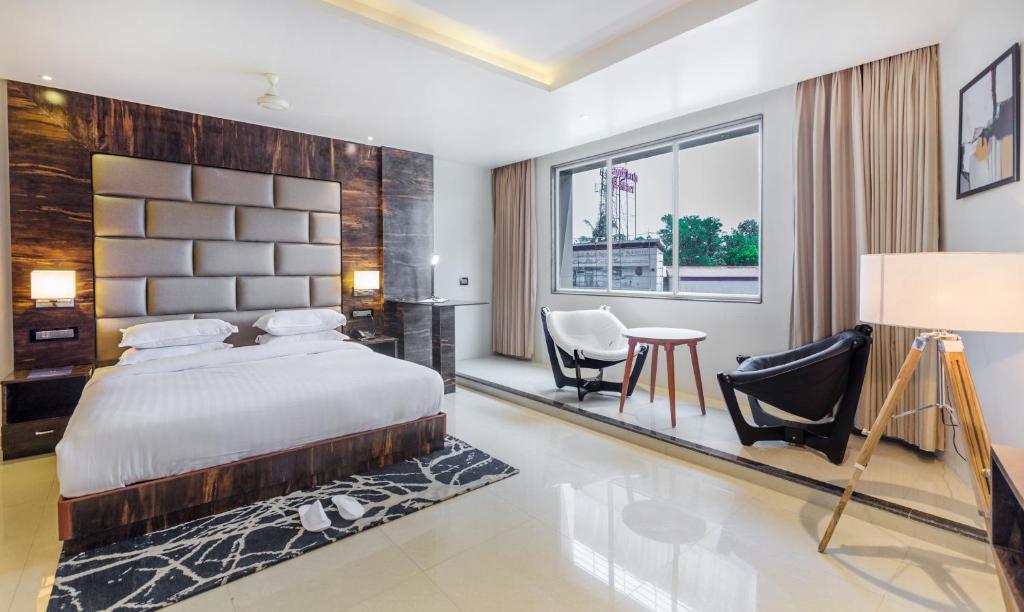 Aura One Hotel في كوتشي: غرفة نوم بسرير وطاولة وكراسي