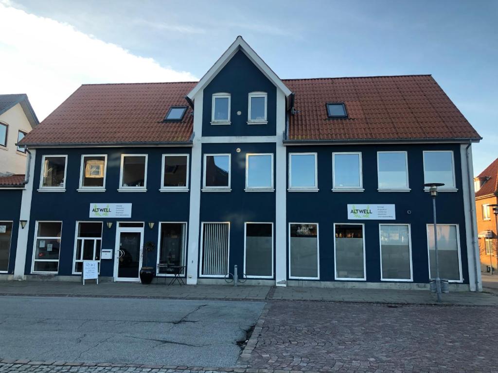 un gran edificio azul con techo marrón en Den Skaldede Kok Guesthouse en Bindslev