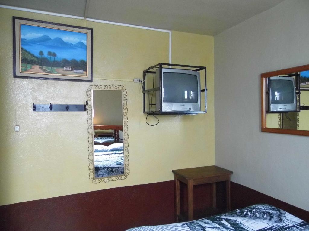 a bedroom with a mirror and a tv and a bed at Hotel Landivar Zona 7 in Guatemala