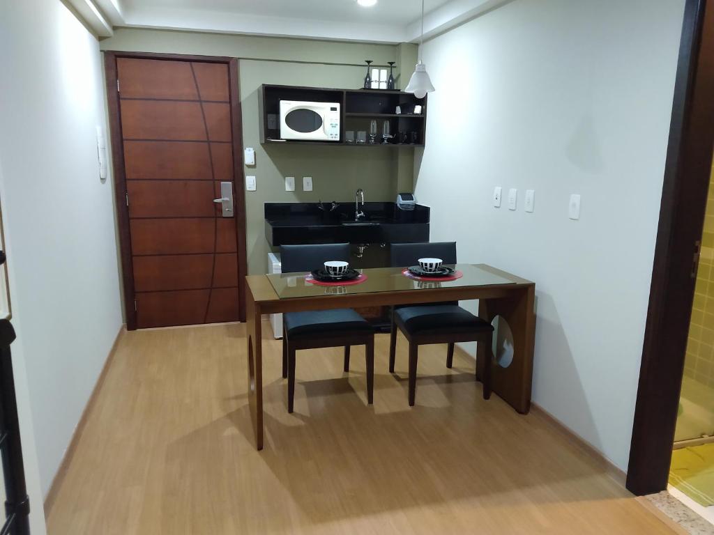 a kitchen with a table and chairs and a microwave at Apt 109 Mont Blanc Apart Hotel in Duque de Caxias