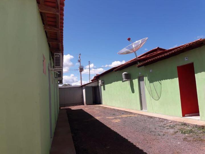 a green building with a fence and a satellite at Pousada Alvorada in Riachão