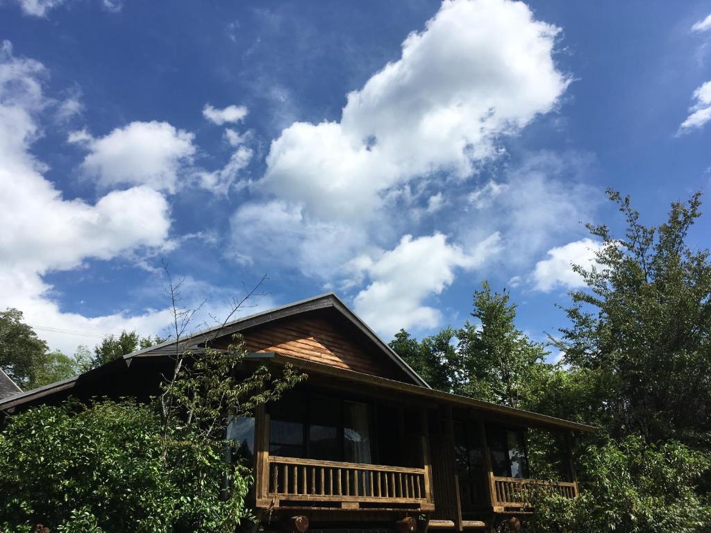 une cabane en rondins avec un ciel bleu et des nuages dans l'établissement 山荘 紗羅樹 Syaranoki, à Yufu