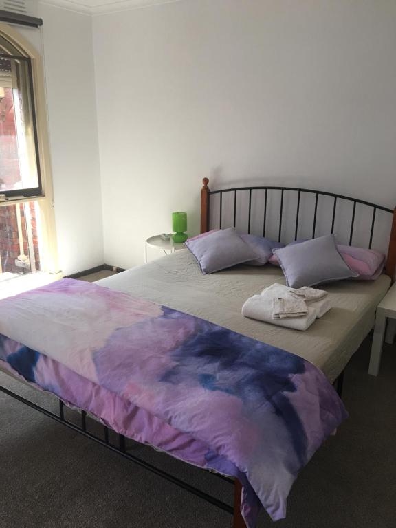 Un dormitorio con una cama grande con sábanas y almohadas púrpuras. en 6677, en Glen Waverley
