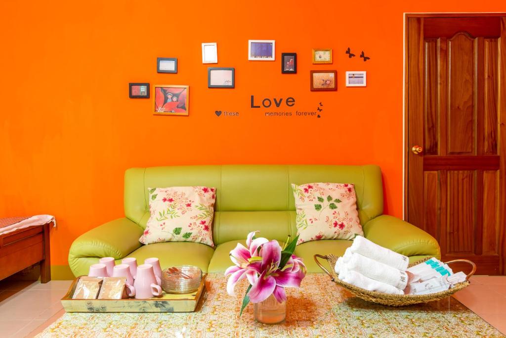 um sofá verde num quarto com uma parede laranja em Heng Bin Bed and Breakfast em Taitung City