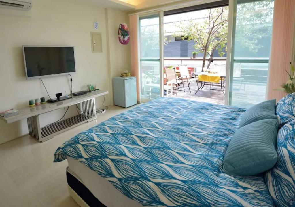 a bedroom with a bed and a television and a patio at Sanyi Wei Wei Feng B&B in Sanyi