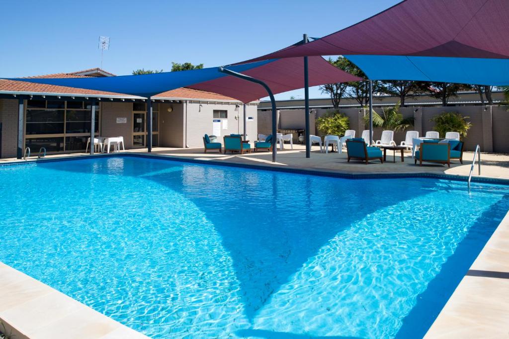 a swimming pool with a blue umbrella on top of it at ibis Styles Geraldton in Geraldton