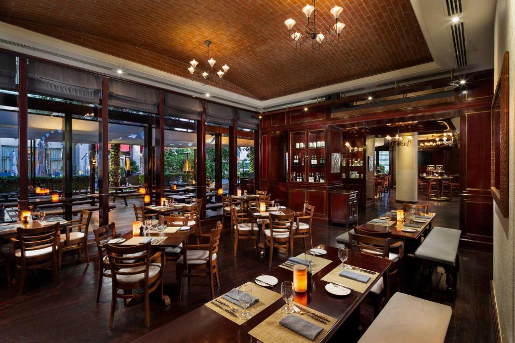 a restaurant with wooden tables and chairs and windows at Beach Rotana - Abu Dhabi in Abu Dhabi