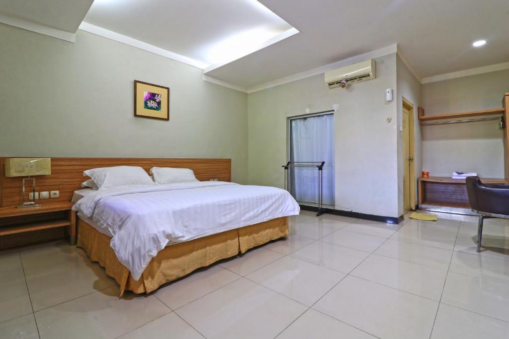 a bedroom with a bed and a desk and a window at Hotel Sampaga in Banjarmasin