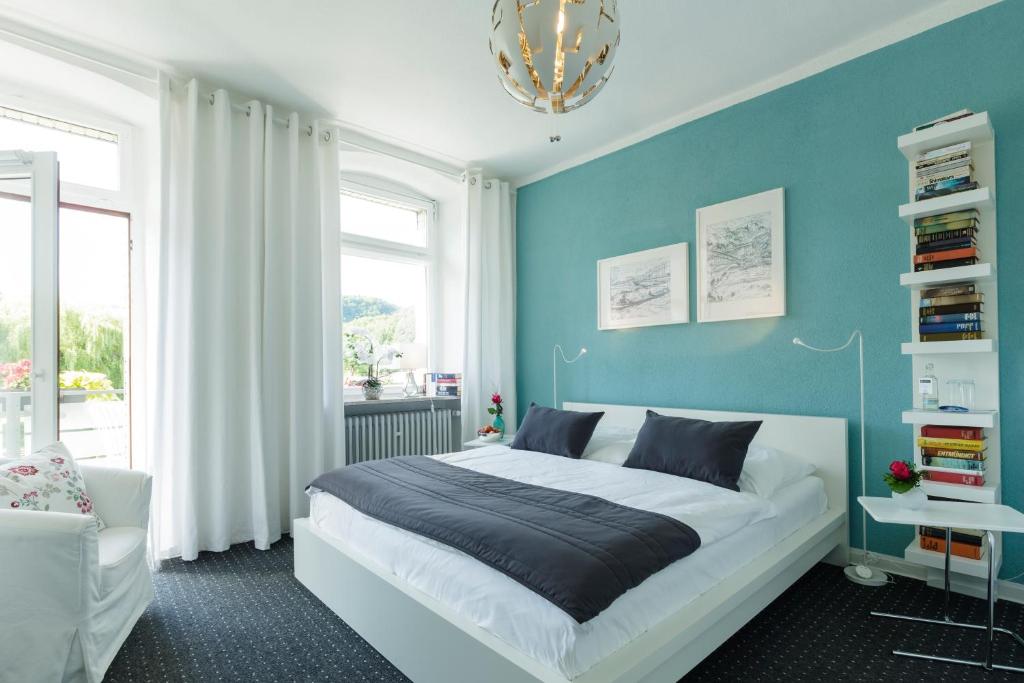 um quarto com uma cama grande e uma parede azul em Hotel am Goetheberg em Obernhof
