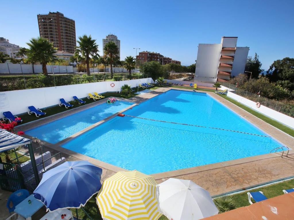 a swimming pool with umbrellas in front of a building at Ocean View Apartments in Portimão