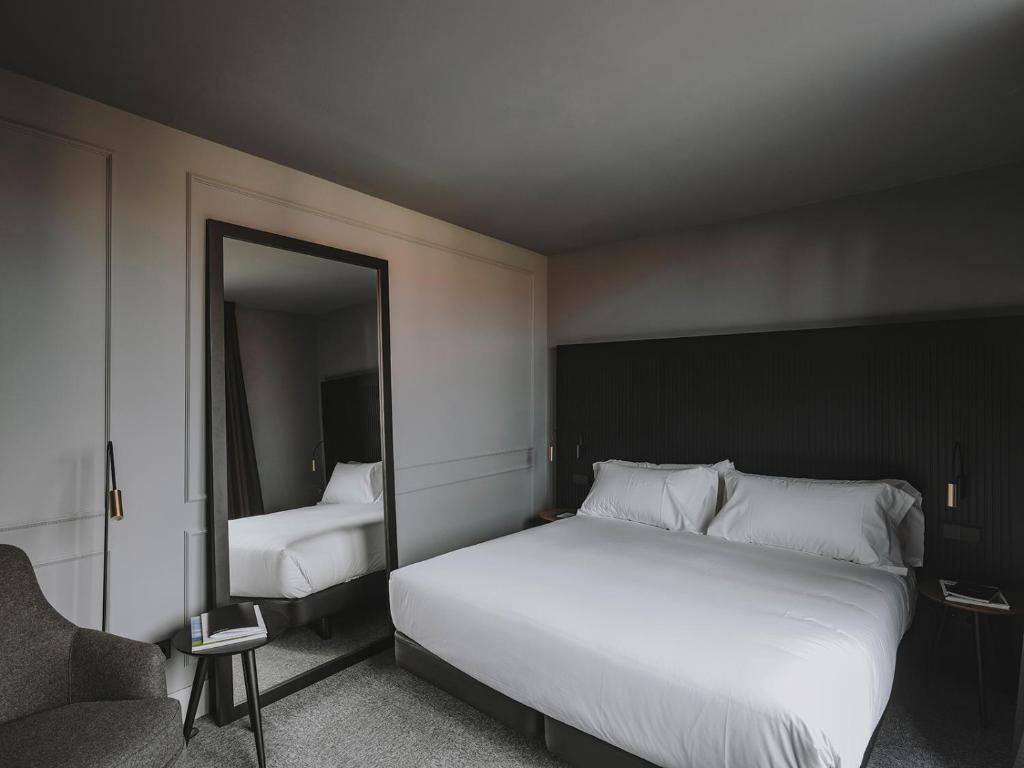 a bedroom with a large white bed and a mirror at El Môderne Hotel in Gijón