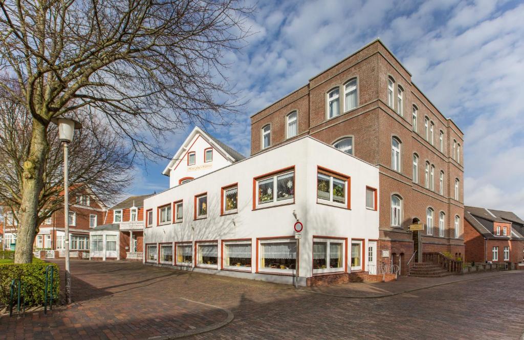 ein Gebäude auf einer Straße mit einem Baum in der Unterkunft Hotel Graf Waldersee in Borkum