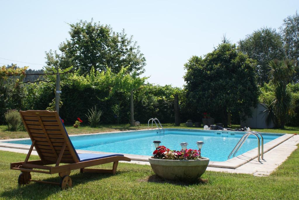 a chair in the grass next to a swimming pool at Quinta de Santa Baia in Gaifar