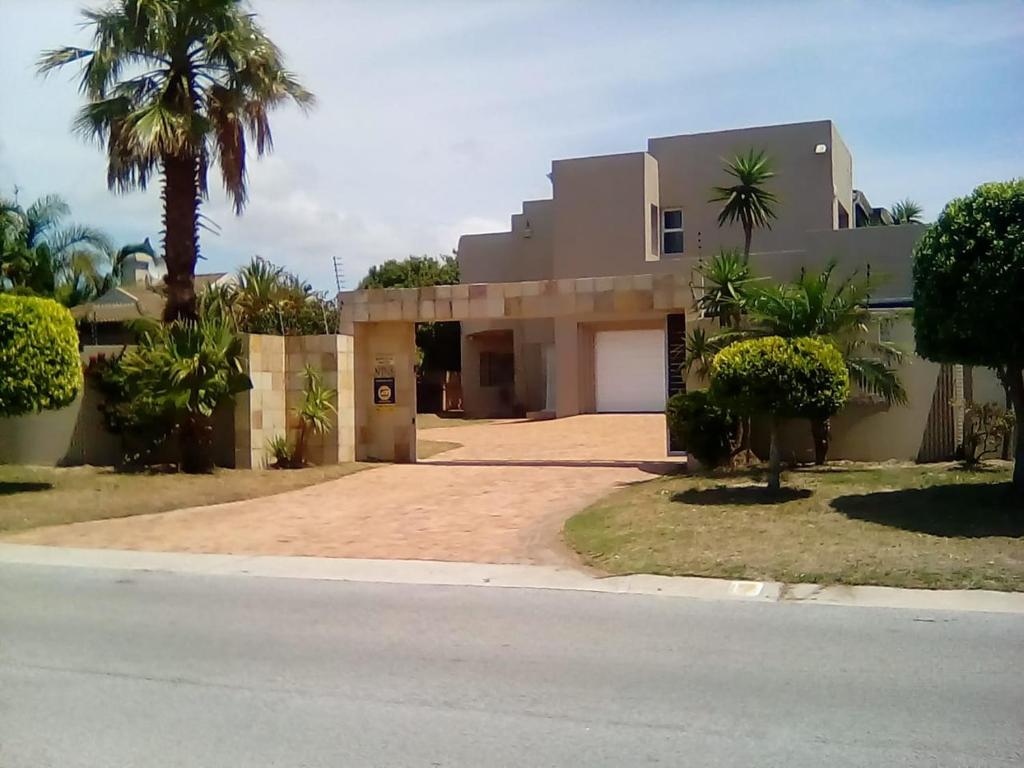 a house with a palm tree in front of a street at Nine On Borghorst in Port Elizabeth