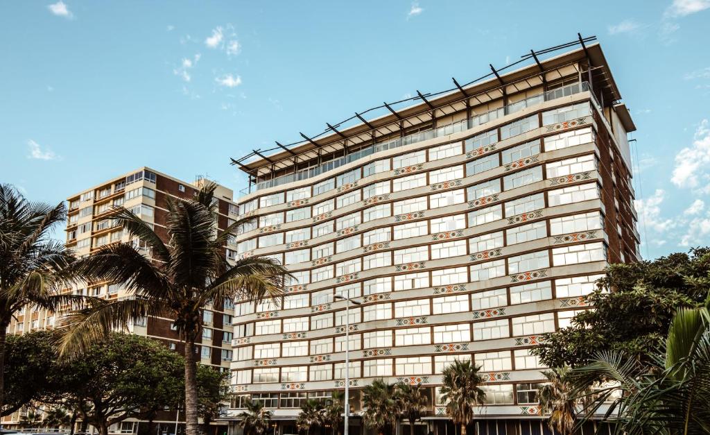 a large building with palm trees in front of it at Belaire Suites Hotel in Durban