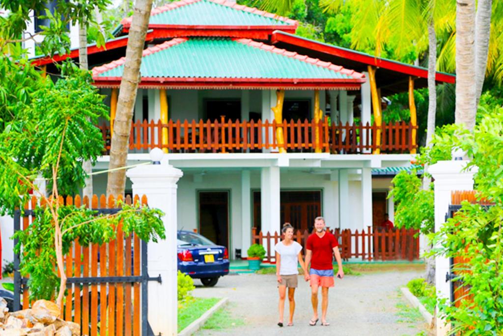 a man and a woman walking in front of a house at Hotel Birds View in Tissamaharama