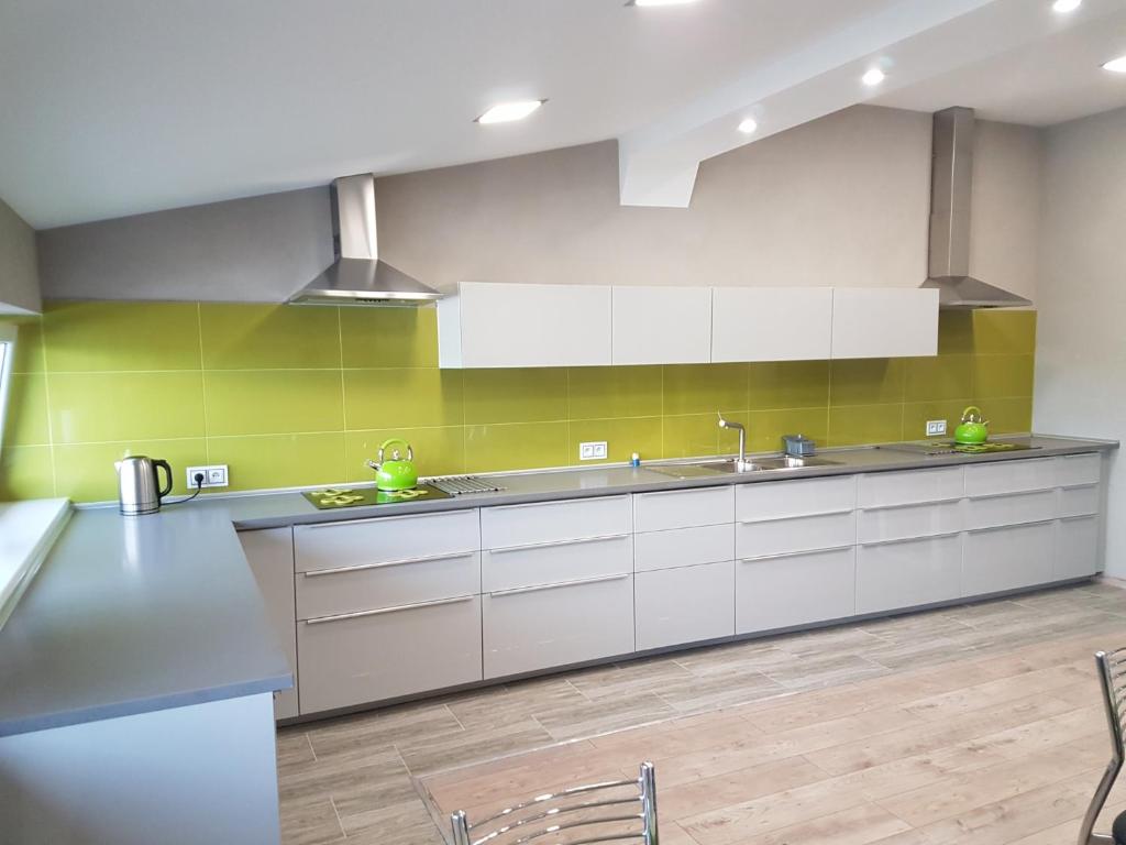 a kitchen with white cabinets and green wall at Budziechów Noclegi in Lubsko