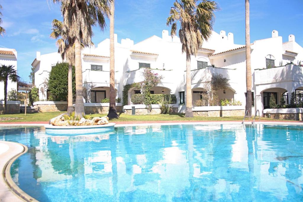a large swimming pool in front of a house with palm trees at Beautiful seafront house in Hospitalet de l'Infant