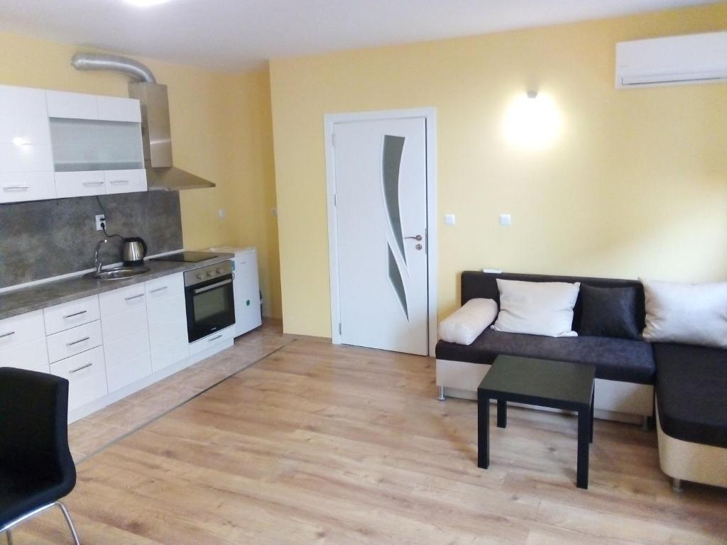 a small living room with a couch and a kitchen at Tvardica Apartment in Burgas