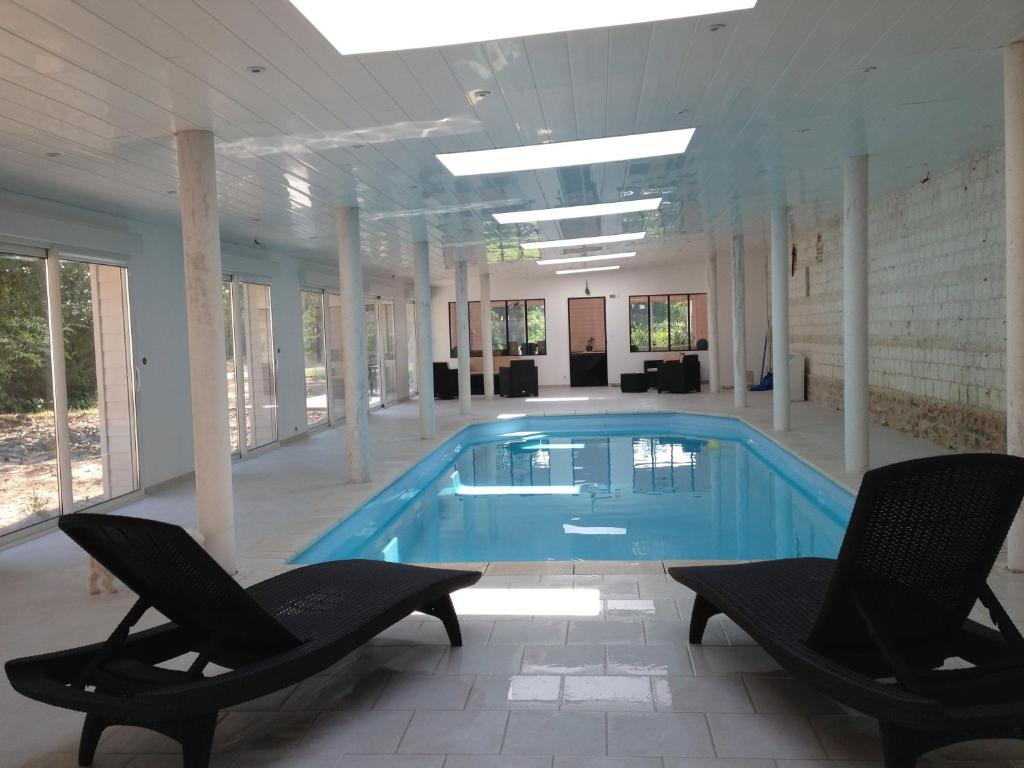 una gran piscina con 2 sillas y una piscina en Les Chambres du Chateau de Grèges, en Grèges