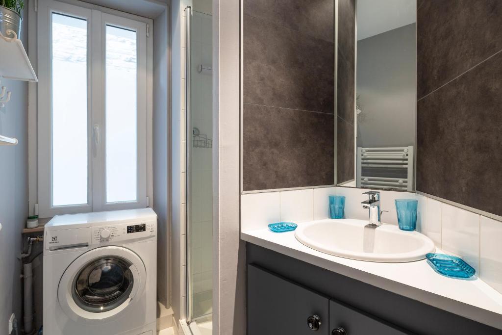 a bathroom with a sink and a washing machine at Le Plongeoir by Cocoonr in Saint Malo