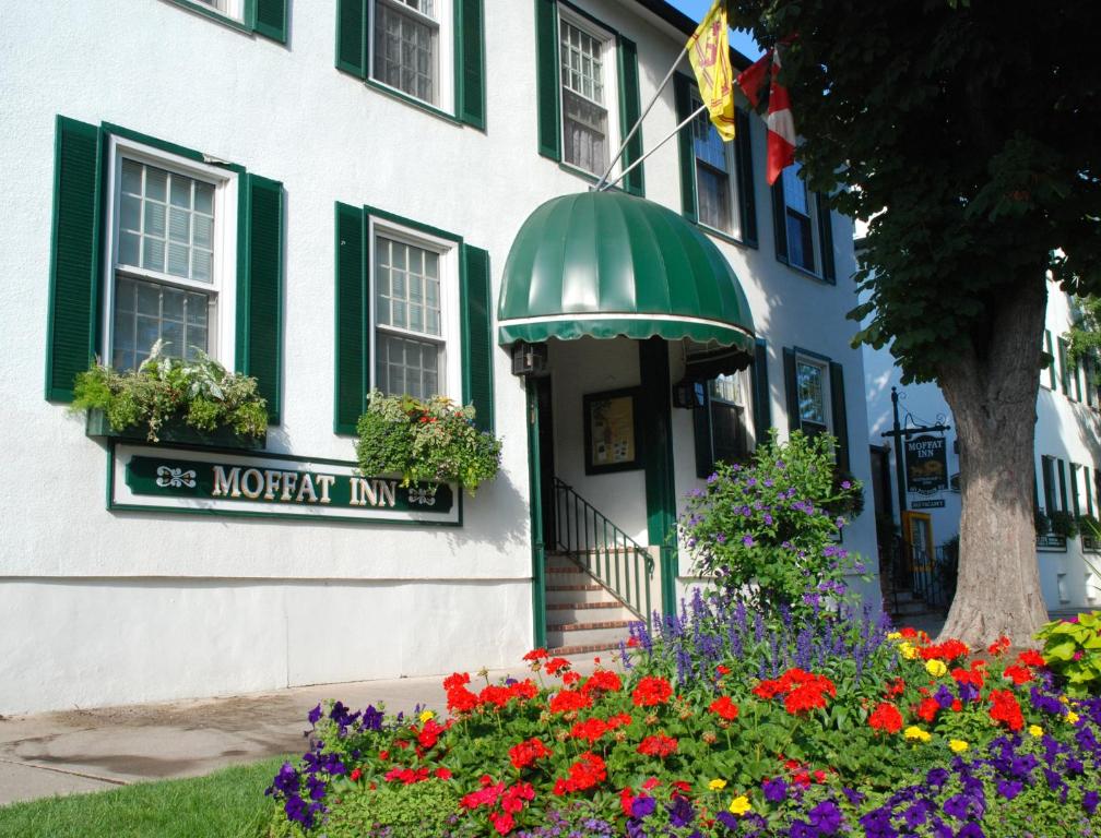 a building with a sign for a morgan inn with flowers at Moffat Inn in Niagara-on-the-Lake