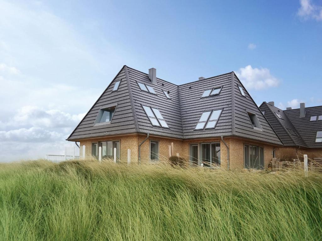 a house in the middle of a field of tall grass at Strandteufel Sylt in Hörnum