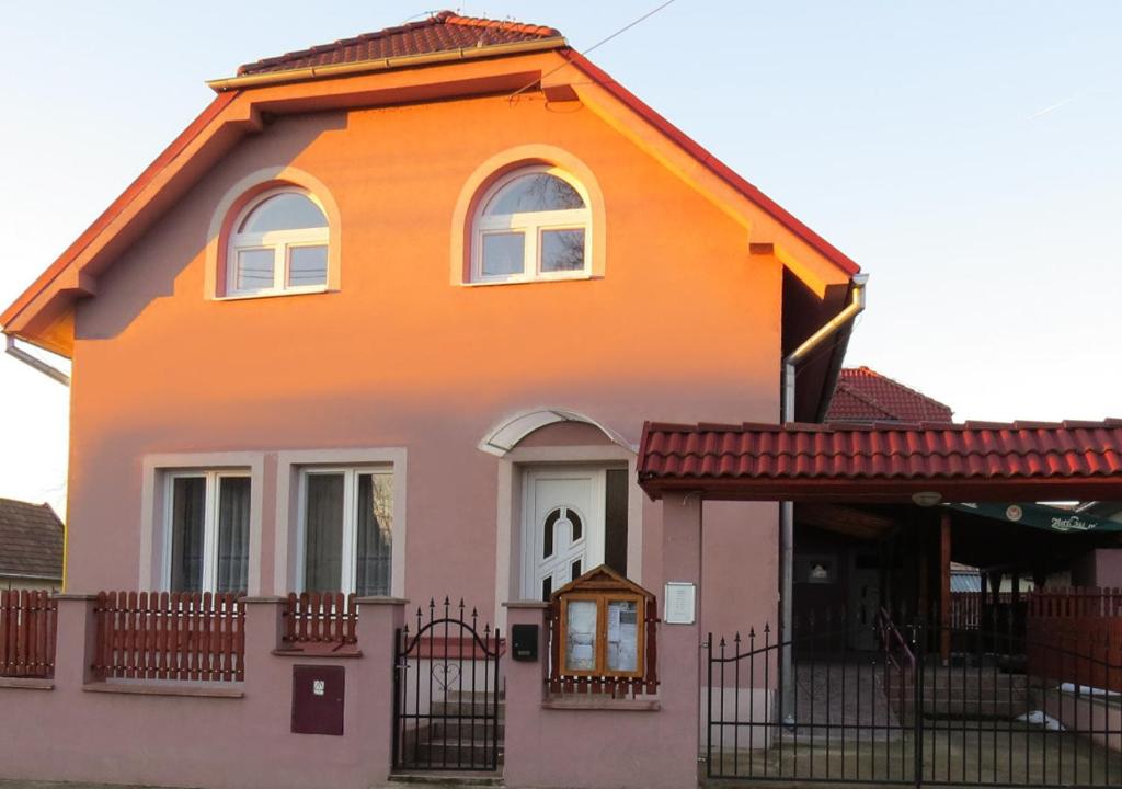 een oranje huis met een hek ervoor bij Penzion - Peri in Hokovce