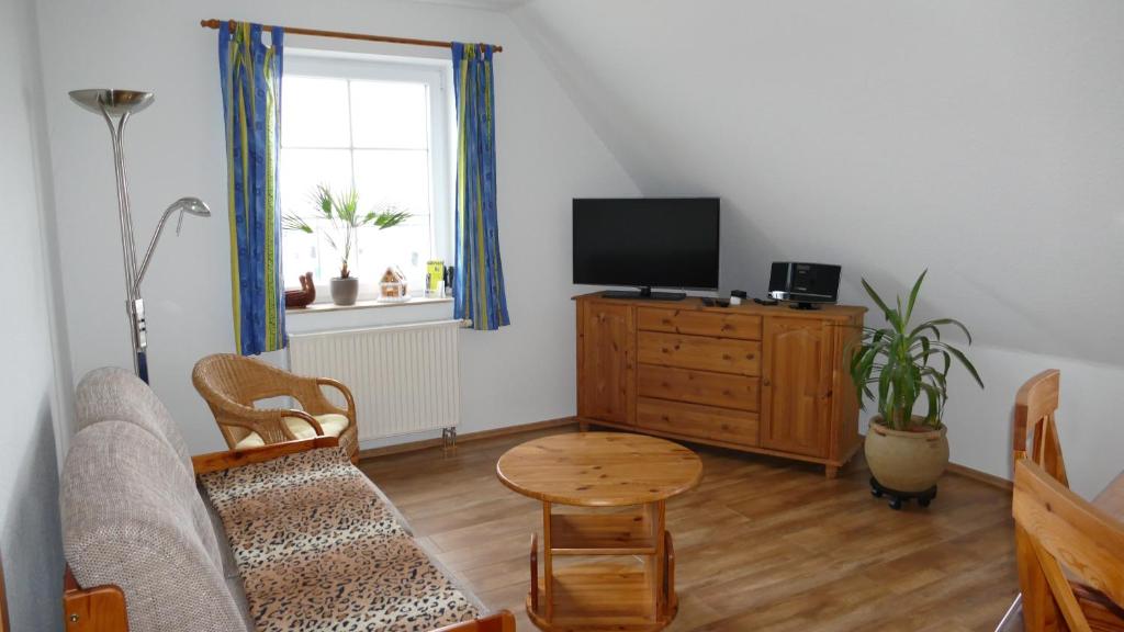 a living room with a couch and a tv and a table at Ferienwohnung 1, Neuendorf - Hiddensee in Neuendorf