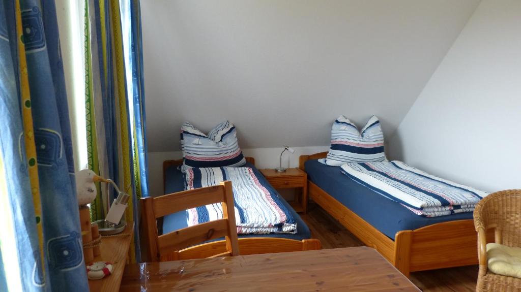 two beds in a small room with a table and chairs at Ferienwohnung 2, Neuendorf - Hiddensee in Neuendorf