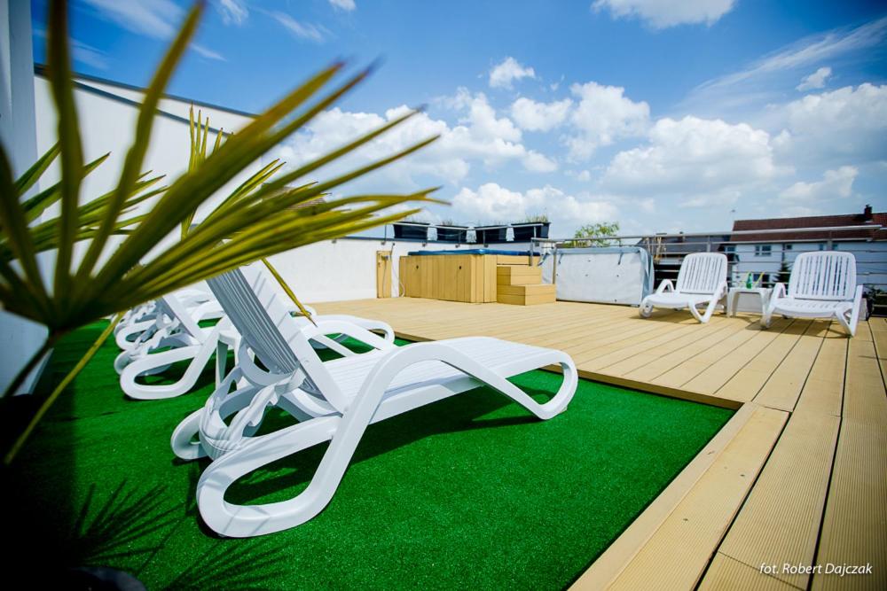 a deck with white chairs and a green rug at Apartamenty Villa Baltica Rewal in Rewal