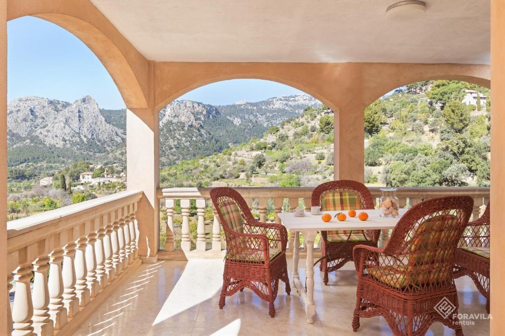 une terrasse couverte avec une table, des chaises et des montagnes dans l'établissement Can Cega, à Bunyola