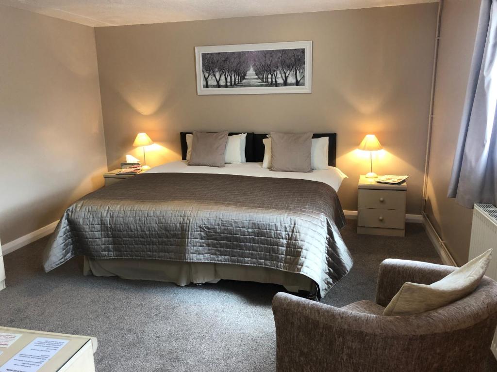 a bedroom with a large bed and two chairs at Newent Golf Club and Lodges in Newent