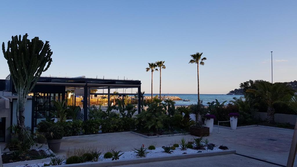 un complejo con palmeras y el océano en el fondo en alex appartement, en Roquebrune-Cap-Martin